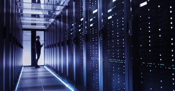 an IT worker checks a row of mainframe computers