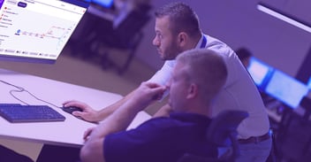 two cloud security techs look at a computer screen displaying Uptycs’ cloud security