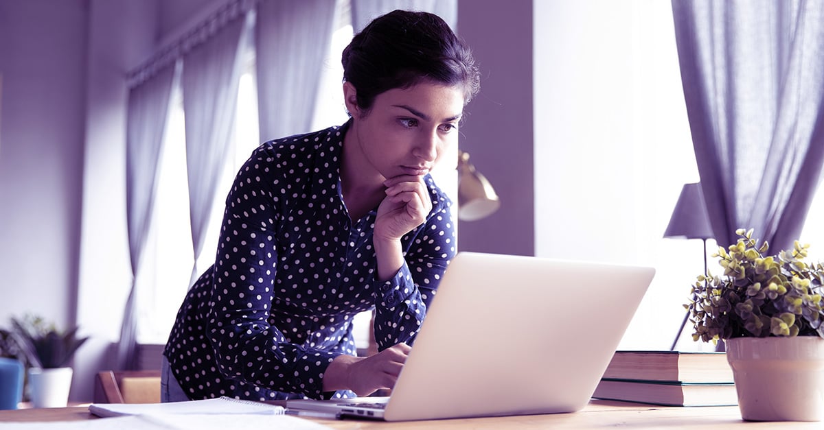 a young woman looks intently at a laptop screen