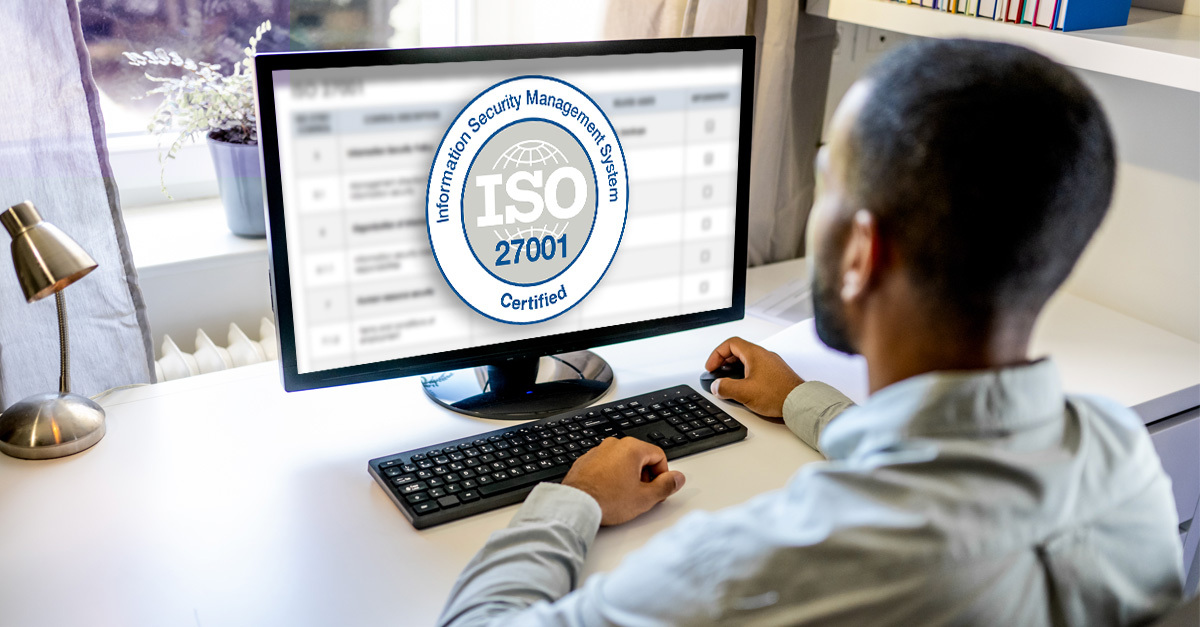 A man looking at ISO 27001 compliance software on a computer screen
