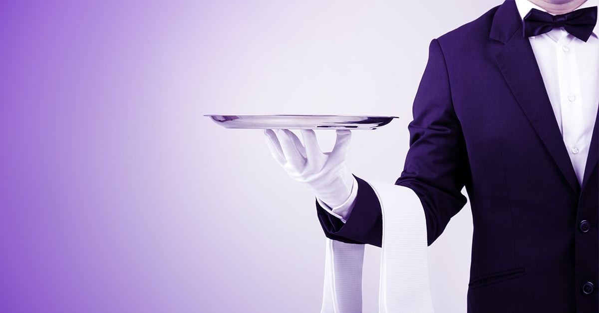 a waiter in a tuxedo holds a tray like a server