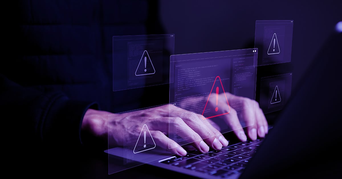 hands on a laptop keyboard overlaid with a warning icon