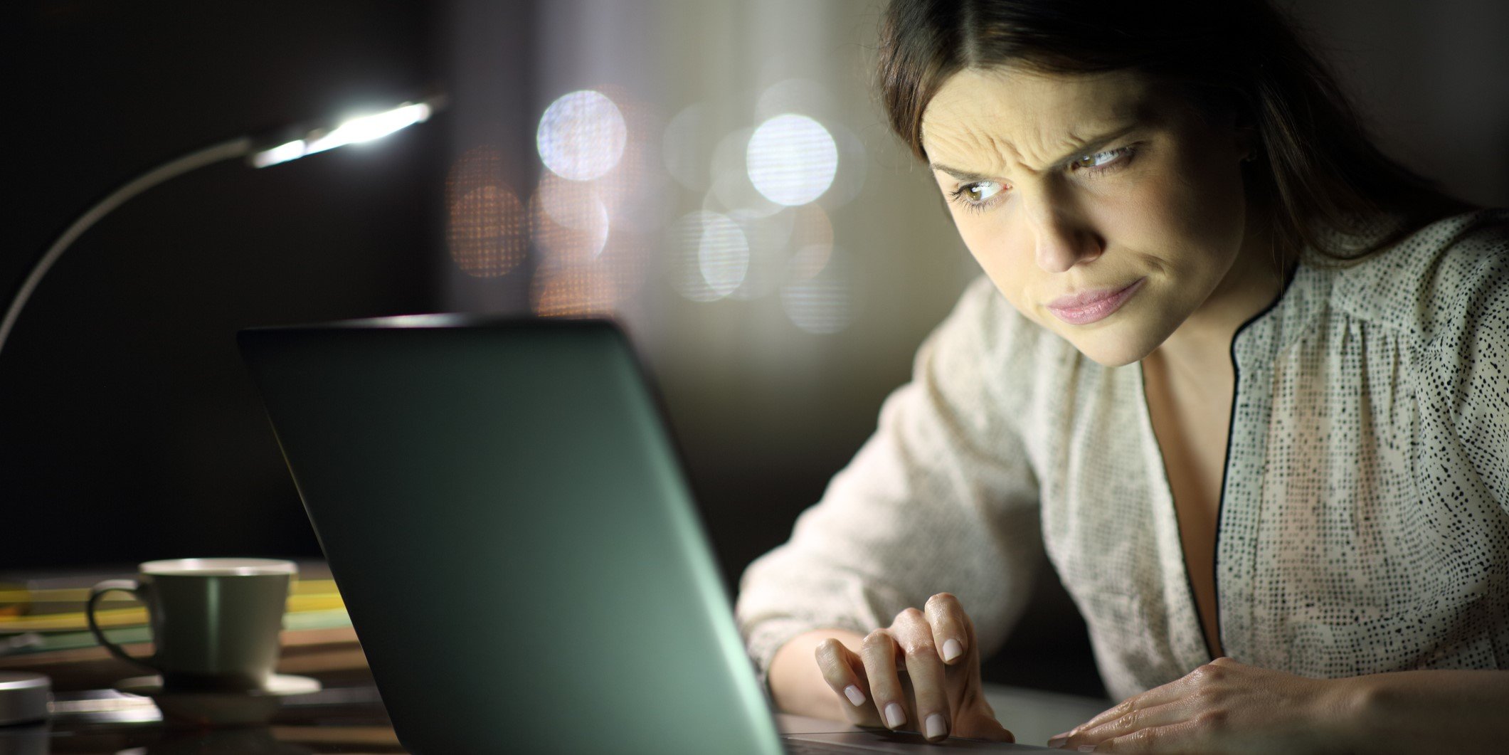 A woman looking at her laptop with a suspicious expression